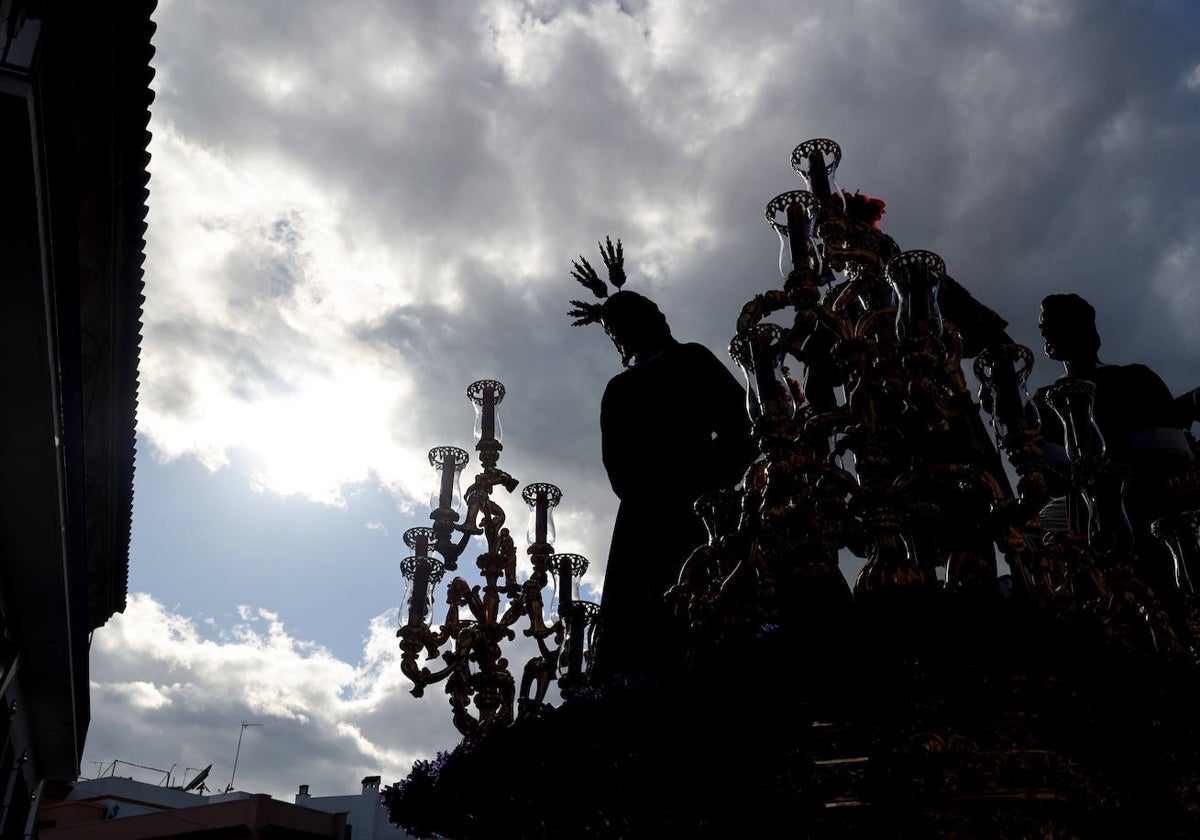 Cielo lleno de nubes, con el Señor de la Sangre a contraluz, el Martes Santo