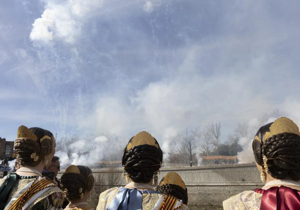 Varias mujeres ataviadas con el traje de fallera acuden a la mascletá realizada en el Puente del Rey de Madrid