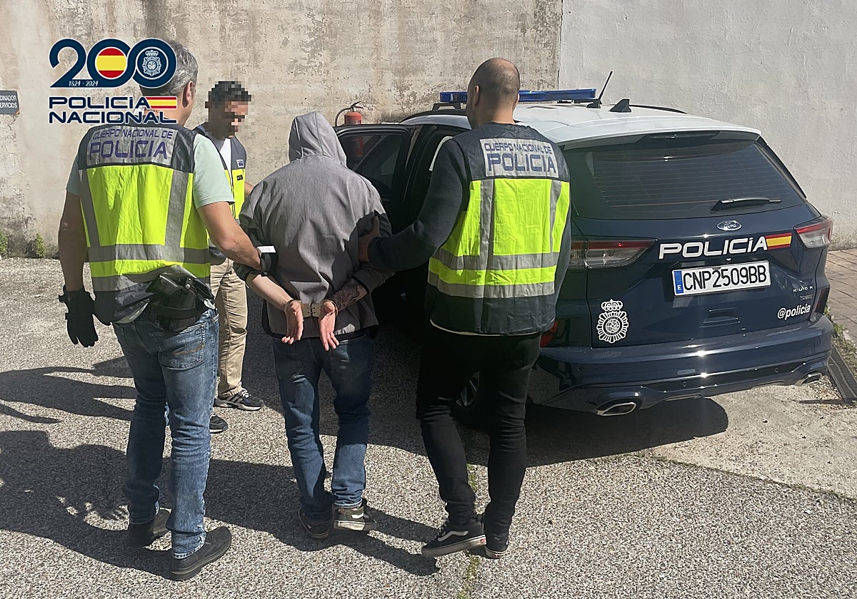 Agentes conducen a uno de los detenidos a un coche policial