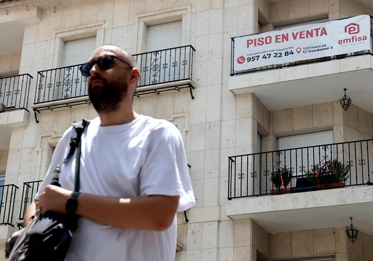 Un hombre pasa delante de un edificio con una vivienda en venta