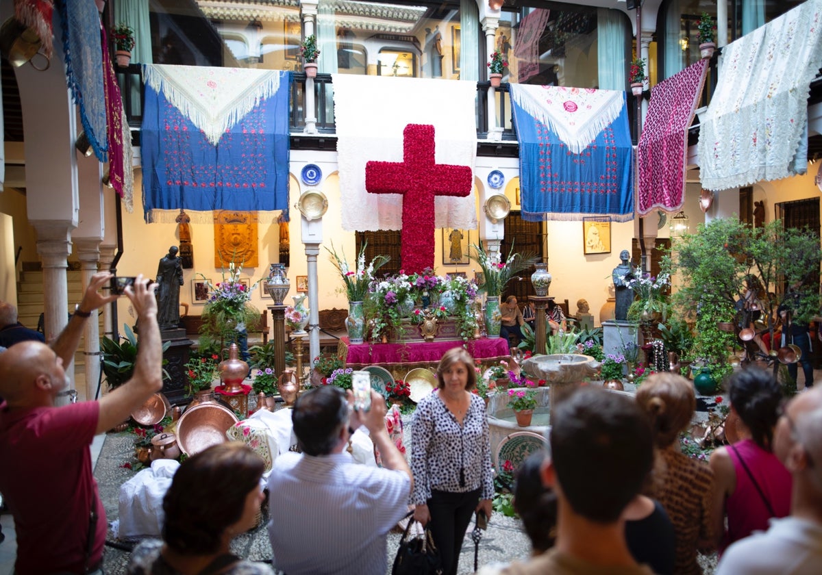 Una cruz en un patio granadino, rodeada de mantones y otros elementos decorativos