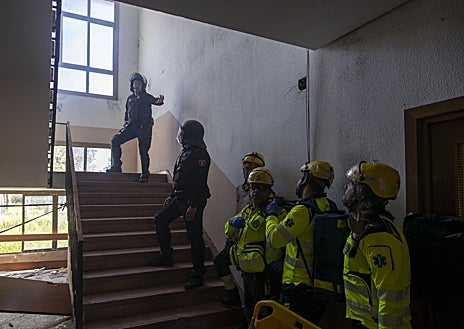 Imagen secundaria 1 - Dos binomios de la CCS, los antidisturbios del Cuerpo local, se acercan al edificio asaltado; los policías marcan el paso a los facultativos, ya dentro del inmueble; y los sanitarios atienden a un joven
