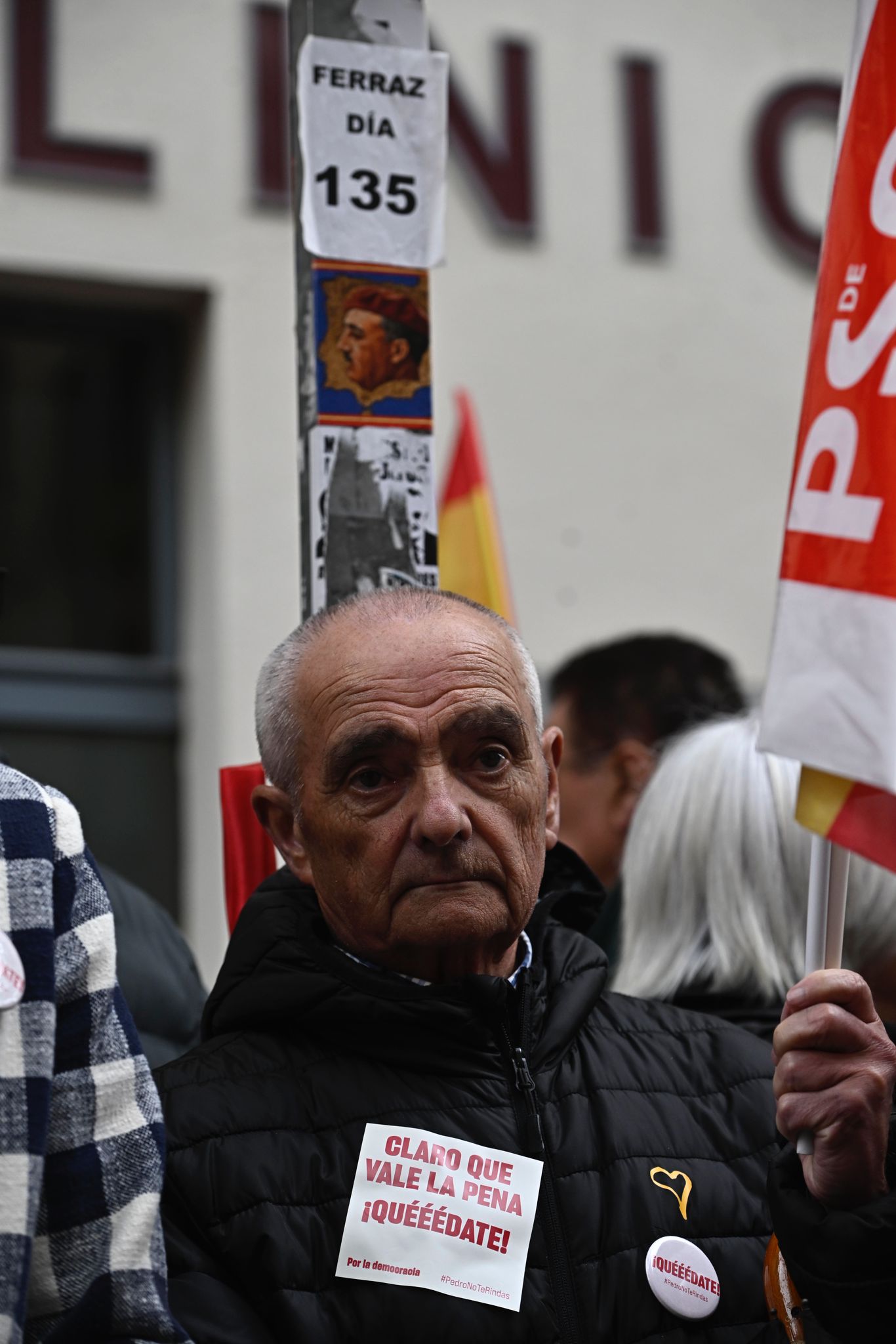 Un simpatizante con consignas en apoyo a Sánchez delante de unas pegatinas de las protestas que han venido desarrollándose desde noviembre