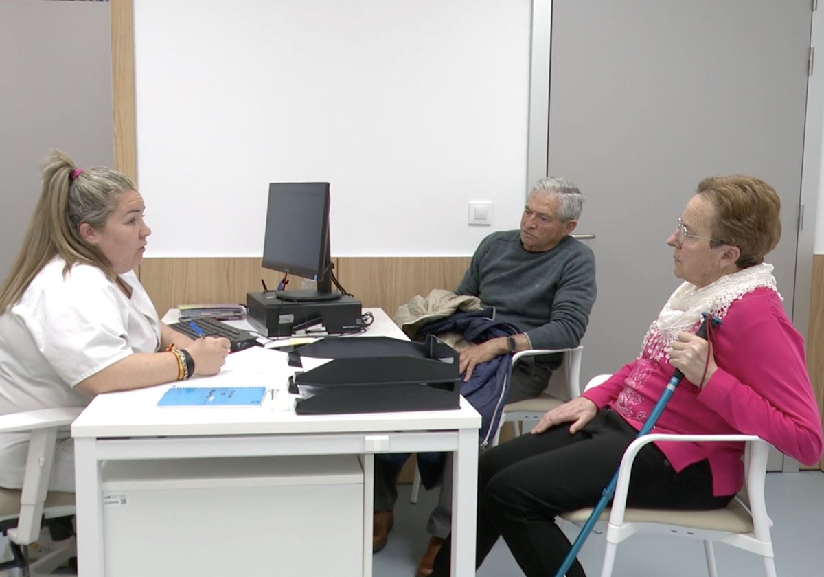 Una profesional sanitaria atiende a una paciente de ELA y su familiar, en el centro de atención diurna del Hospital Zendal