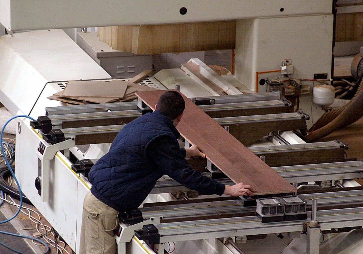 Un trabajador manipula un tablón en una fábrica