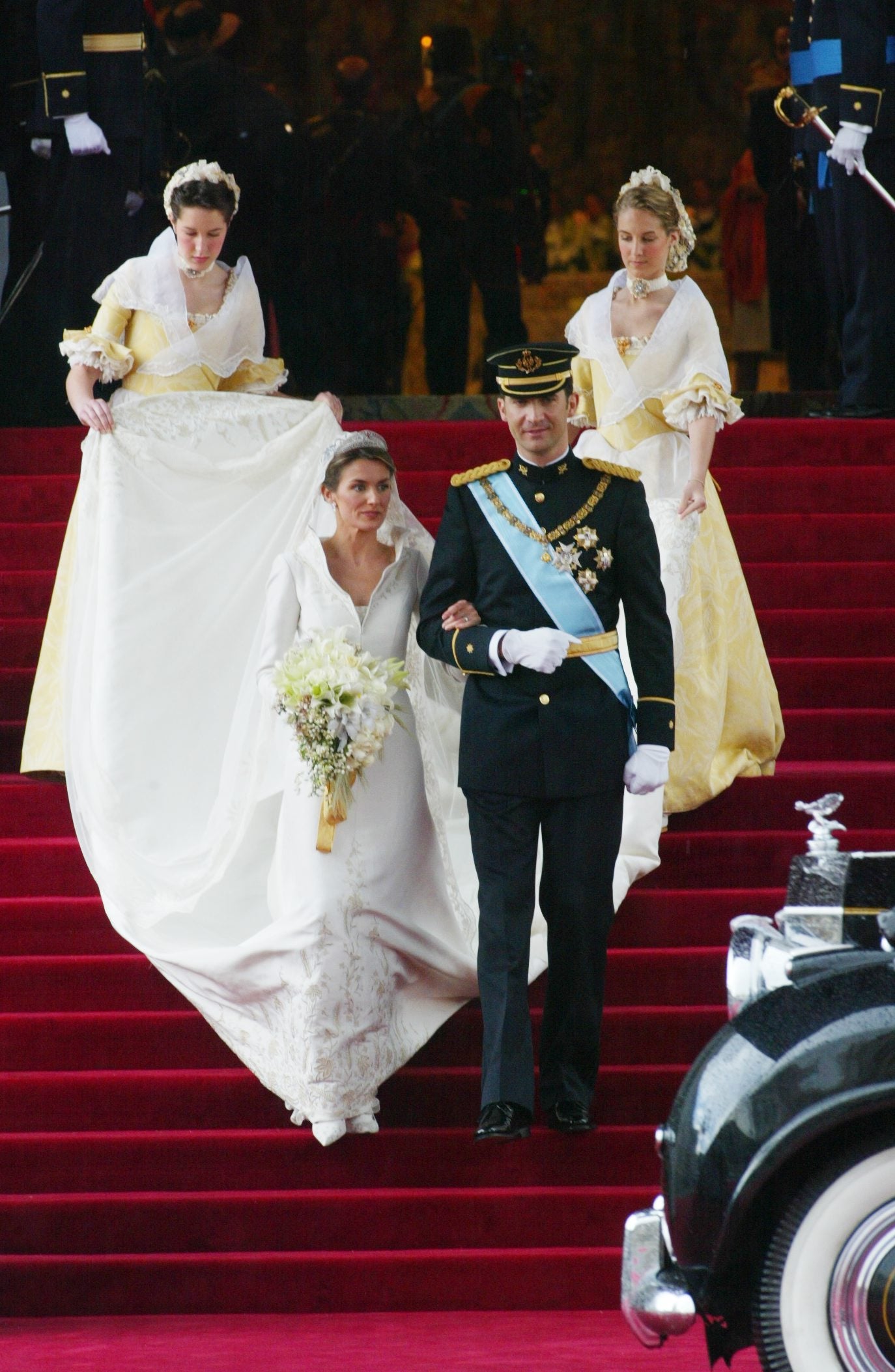 Al finalizar la ceremonia, los Reyes se dirigieron a la salida de la iglesia. Tras recorrer el pasillo de sables, se dispusieron a saludar a la multitud de españoles que ansiosos aguardaban bajo la lluvia. Tras bajar las escaleras del templo donde Don Felipe y Doña Letizia habían contraído matrimonio, tal como se puede apreciar en la imagen, el Rey le indicó a la Reina que se cambiara el ramo de mano para que pudiera saludar a todos los allí presentes. Doña Letizia, de inmediato, obedeció las indicaciones de su recién estrenado marido. 