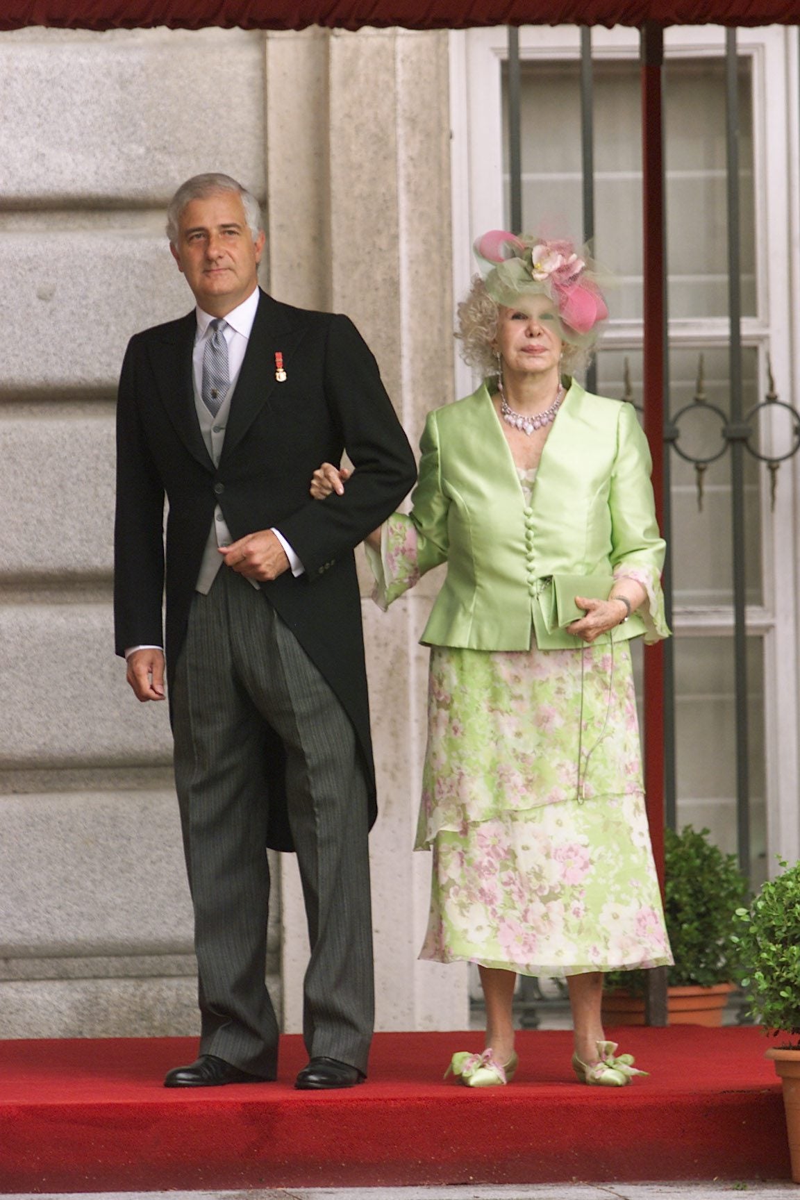 Cayetana de Alba asistió a la celebración del brazo de su hijo Alfonso Martínez de Irujo, duque de Aliaga. La duquesa de Alba lució un llamativo vestido con un estampado floral y mangas evasé de color verde lima, a juego con una chaqueta de satén del mismo color. 