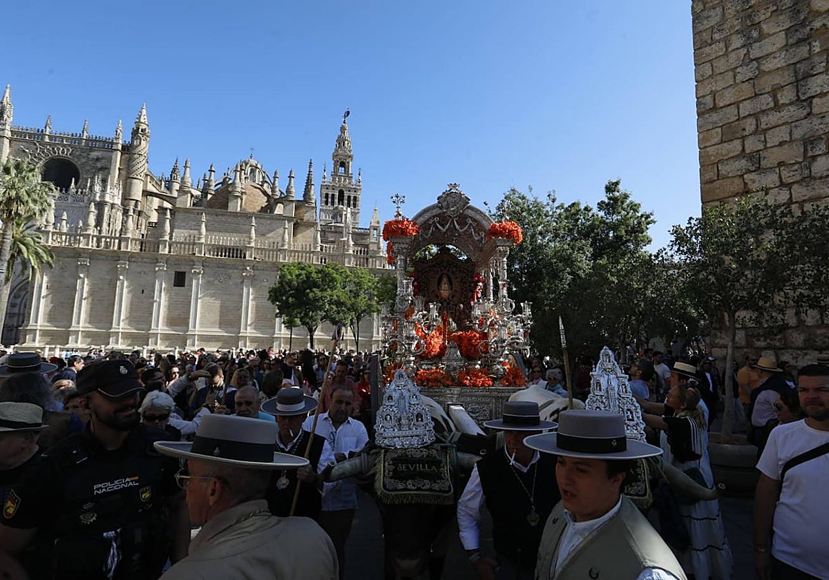 La carreta de la hermandad del Rocío de Sevilla-El Salvador deja la plaza del Triunfo, con la Catedral y la Giralda al fondo