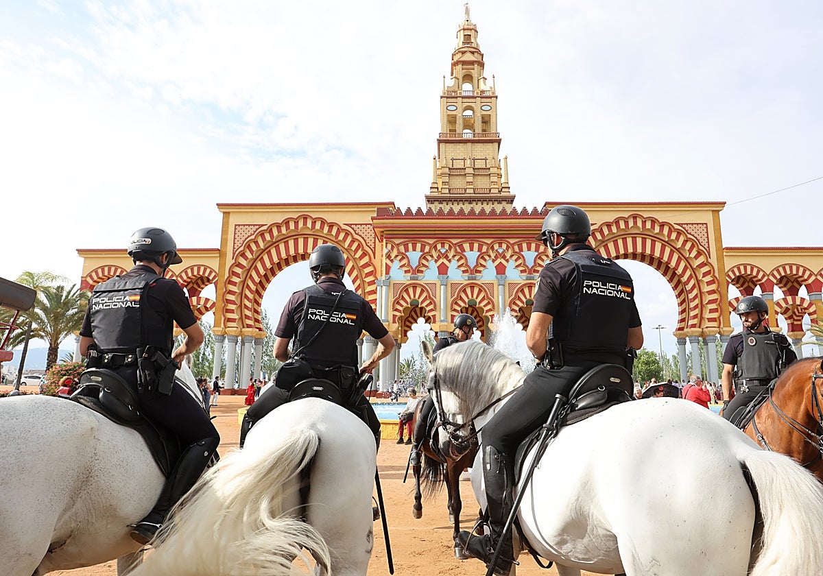 Tres agentes de Policía Nacional a caballo frente a la portada de la Feria de Córdoba