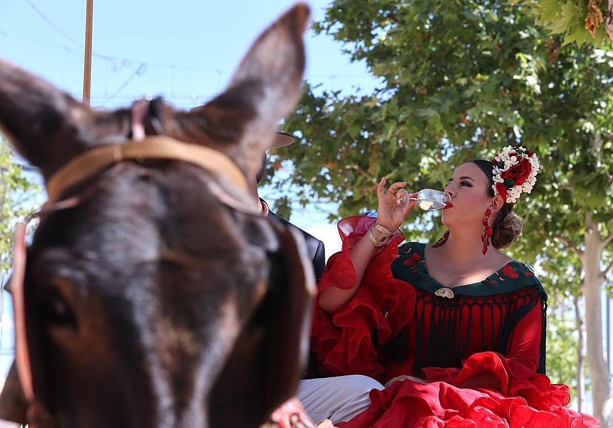 Una flamenca toma una copa de vino en la Feria de Córdoba