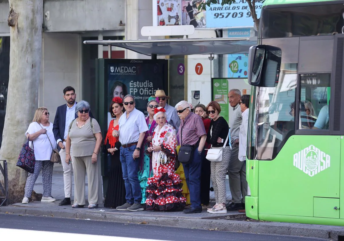 Varias personas, el jueves esperando en una céntrica parada el autobús para ir a la Feria