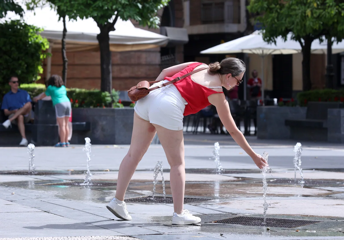 Una joven se refresca con los chorros de la plaza de las Tendillas