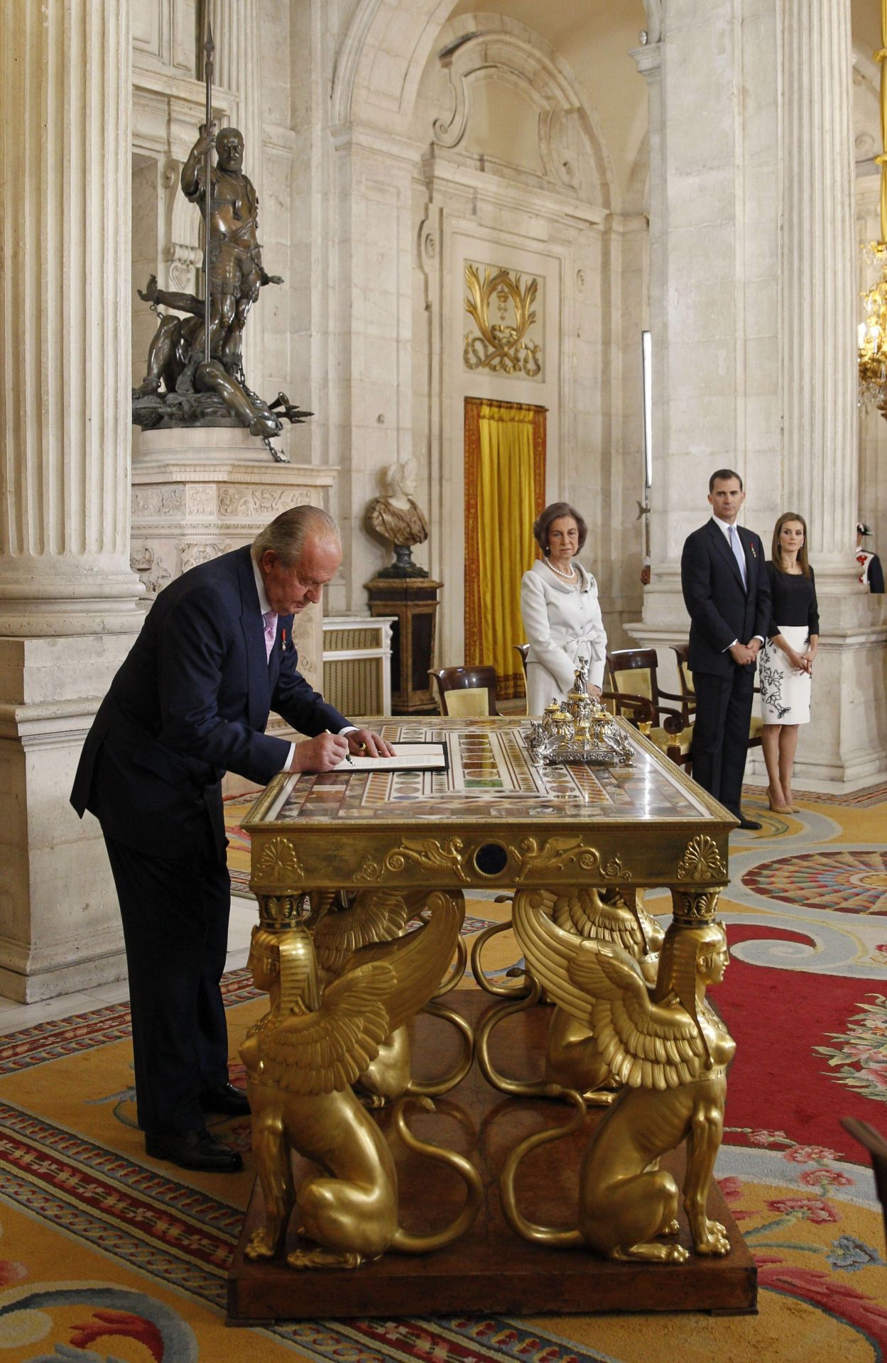 La tarde del 18 de junio de 2014, el Rey Juan Carlos firmó en la mesa de las esfinges del salón de Columnas del Palacio Real la Ley Orgánica que hizo efectiva esa misma medianoche su abdicación en su hijo. La firma se produjo en presencia de Doña Sofía, los entonces Príncipes de Asturias y sus hijas, y los principales representantes de la política española y altos poderes del Estado, en una solemne ceremonia. Tras esta, Don Juan Carlos abrazó a Don Felipe y al resto de sus familiares allí presentes ante la presencia de más de 150 invitados.