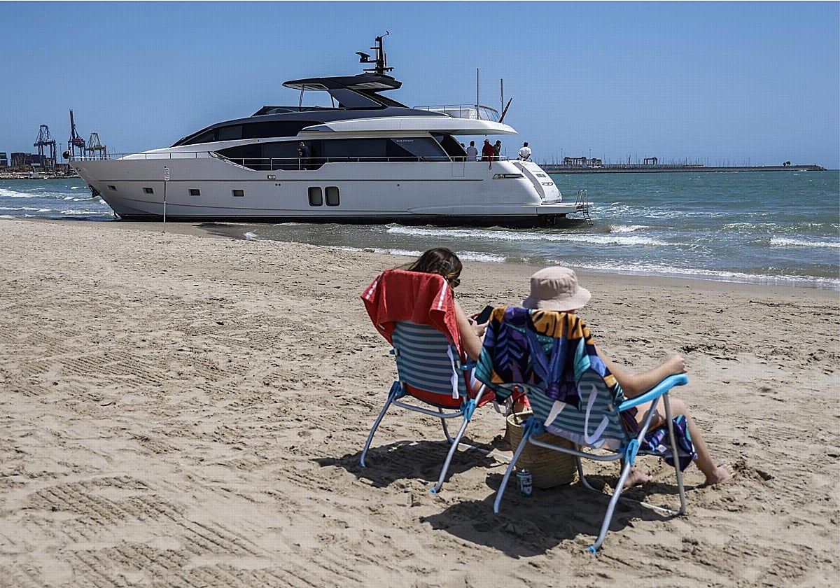 Bañistas en la Playa de Pinedo delante de un yate varado en VALENCIA