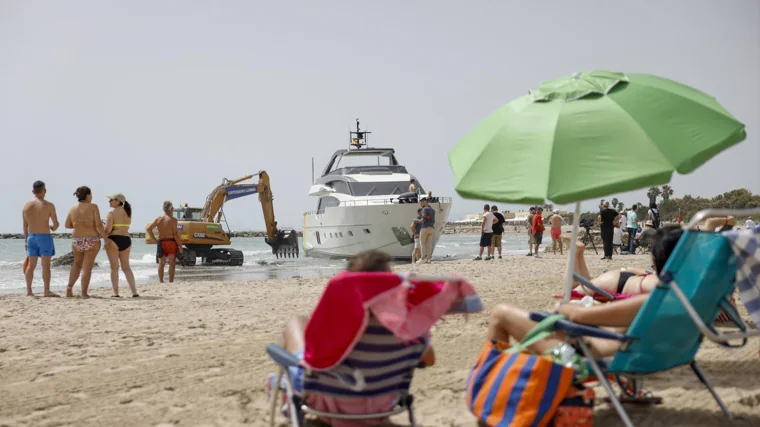 Bañistas y el yate varado en la playa valenciana de Pinedo