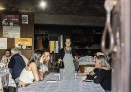 Charo sirve vino a cuatro jóvenes sentados en una mesa de su furancho, en Marín (Pontevedra)