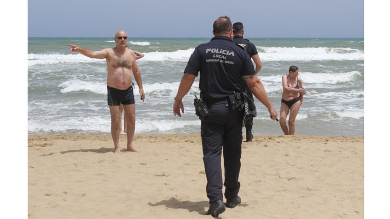 Agentes de la Policía Local y bañistas en la zona donde murieron dos turistas extranjeros el pasado viernes en Guardamar del Segura.