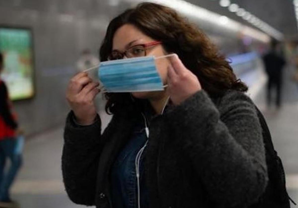 Una joven se pone la mascarilla en un espacio público