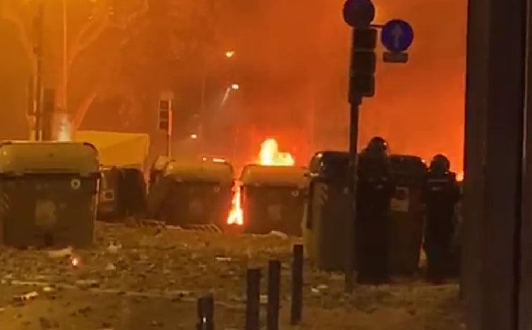 Imagen principal - Arriba, los contenedores incendiados de la plaza de Urquinaona. Abajo, los policías (entre ellos Ángel Hernández, defendiendo la comisaría de la Policía Nacional de Vía Laietana. Al lado, un compañero acompaña a Hernández hacia retaguardia mientras anda encogido, doliéndose, camino de la furgoneta.