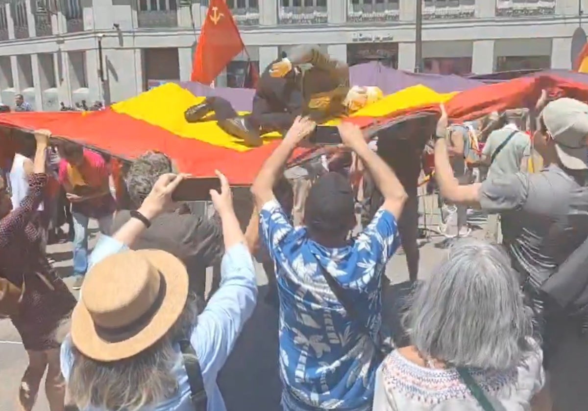 Parte de los asistentes a la manifestación mantean un muñeco de Felipe VI