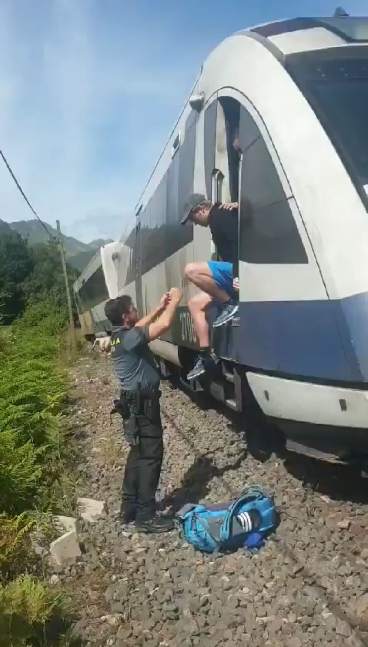 Un agente de la Guardia Civil ayuda a un joven a bajar del tren.
