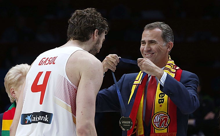 Imagen principal - Arriba, Don Felipe entrega la medalla a Pau Gasol tras ganar España el Europeo 2015. Sobre estas líneas, Don Felipe y Doña Letizia en el velódromo de los Juegos Olímpicos de Atenas, en 2004, y Don Felipe en los Juegos Olímpicos de Barcelona 92