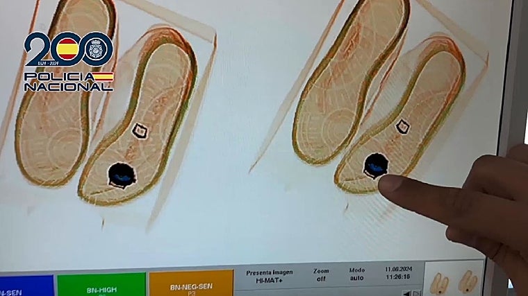 Un agente señala el reloj detectado en la zapatilla en un escáner