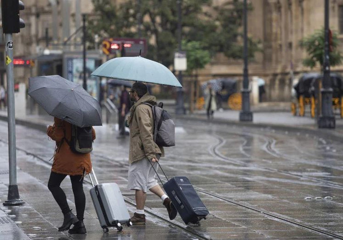 Dos turistas bajo la lluvia en la avenida de la Constitución