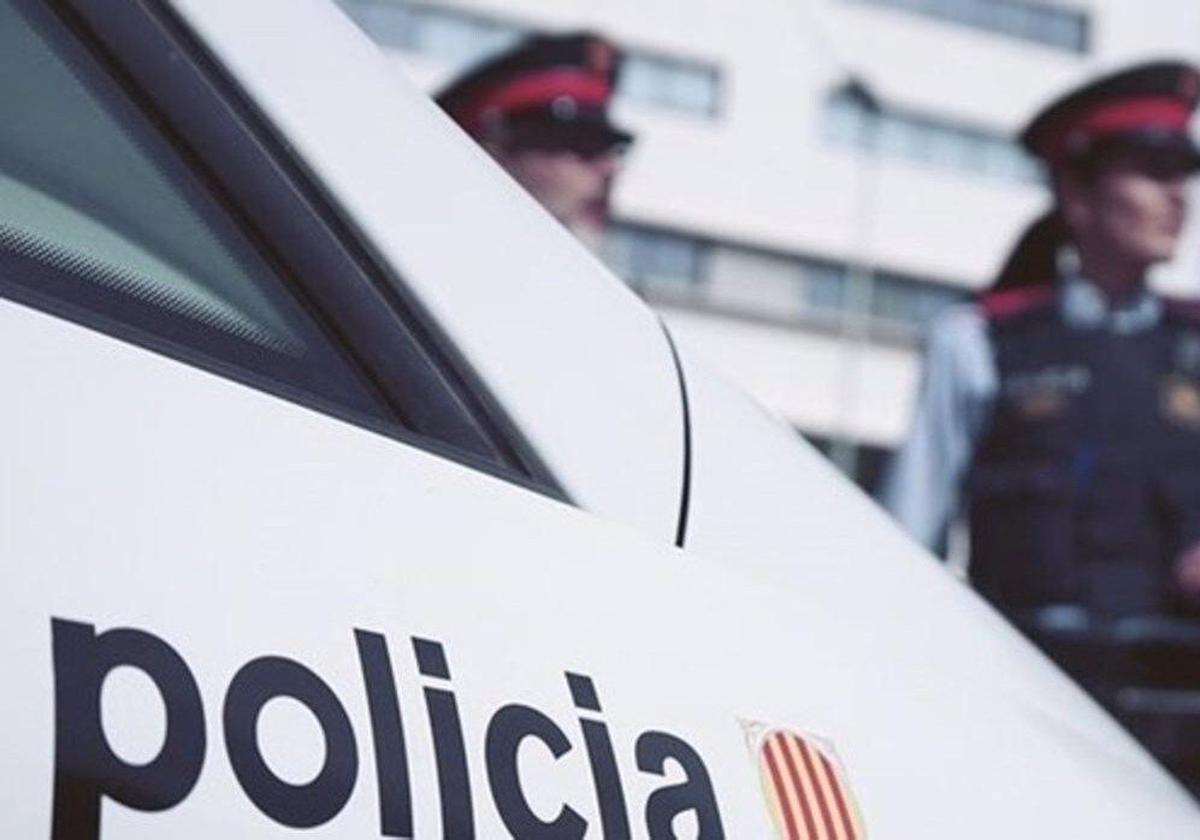 Dos agentes de la Policía catalana junto a un coche patrulla