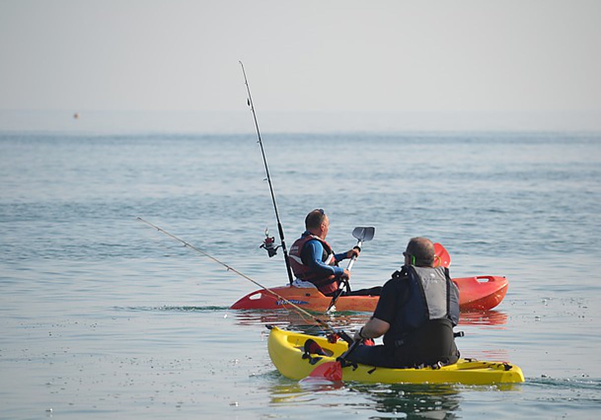 Unos pescadores en la playa montados en un kayak