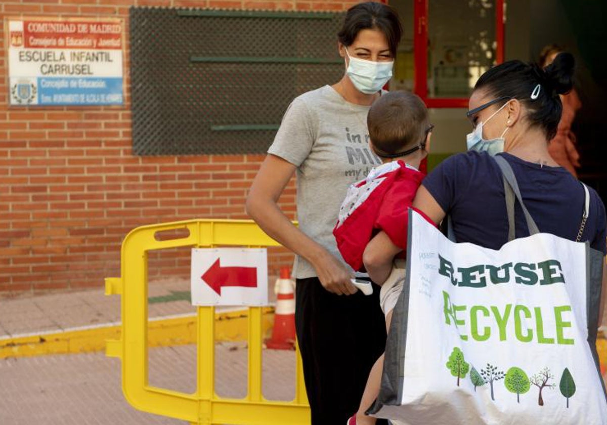 Una madre lleva a su hijo a una escuela infantil en Madrid