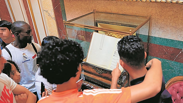 Menores inmigrantes contemplan un ejemplar de la Constitución