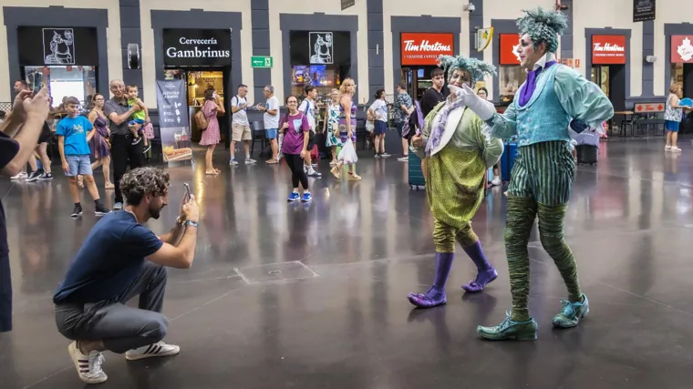 Viajeros en la estación del tren de Alicante junto a la representación del Cirque du Soleil