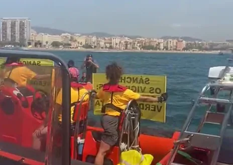 Imagen secundaria 1 - Arriba, una de las embarcaciones de Greenpeace, vista desde la barca policial. Abajo, los activistas desplegando las pancartas. Y, al a derecha, un urbano achicando agua de su lancha