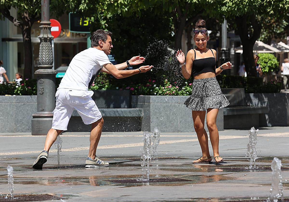 Dos jóvenes juegan con el agua en Las Tendillas durante una jornada calurosa