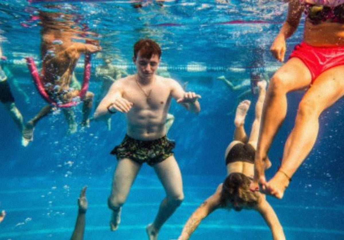 Varios espectadores se sumergen en la piscina para escuchar la música