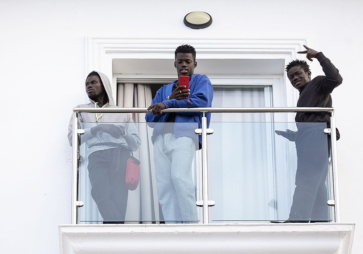 Inmigrantes irregulares saludan desde la terraza de una habitación del hotel Urban Beach de Torrox