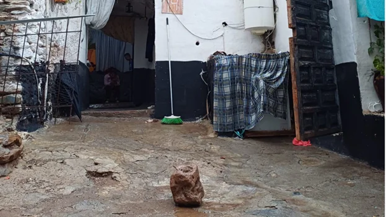 Una piedra de grandes proporciones, desprendida de la ladera delante de unas casas