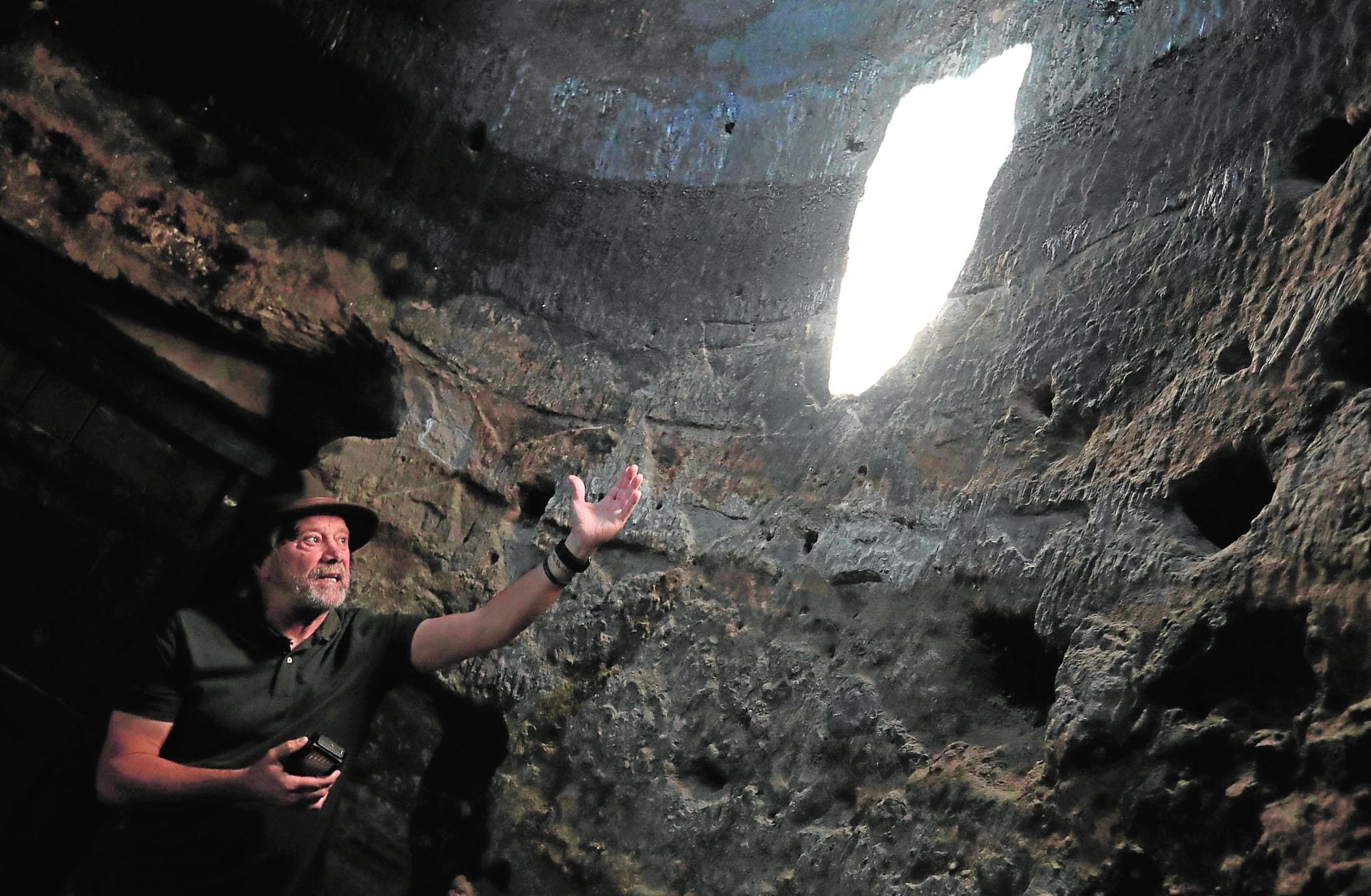 El arqueológo Julio Cuenca señala los grabados con forma de triángulo púbico que la luz del amanecer va recorriendo en el interior de la cueva desde el equinoccio de primavera hasta el equinoccio de otoño