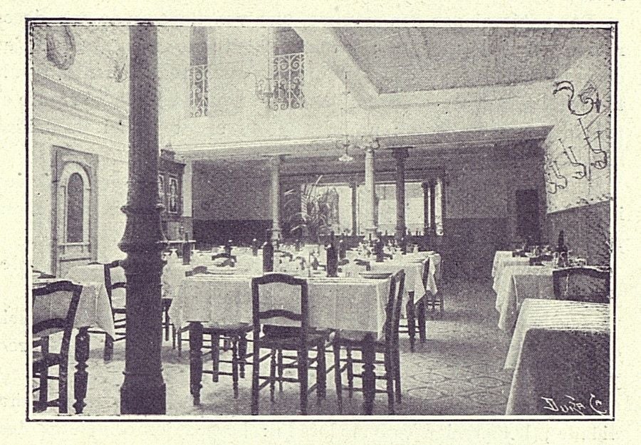 Comedor del Hotel Toledano con el patio acristalado y distintos tipos de mesas. Al fondo, se percibe iluminada la entrada ante la cuesta del Alcázar. Fotografía publicada en la "Guía práctica de Toledo y su provincia" (ca. 1907)