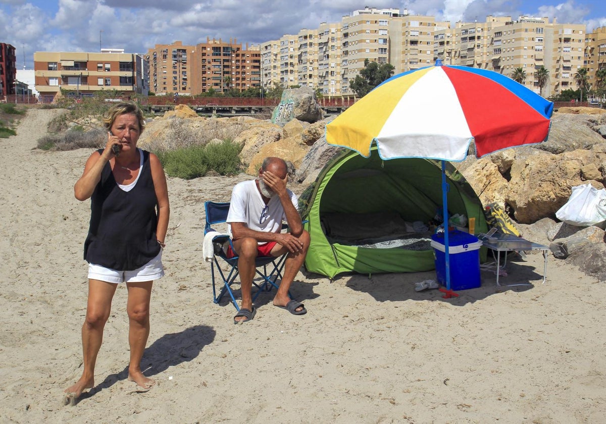 Charo y José Vicente, junto a la sombrilla y los enseres que utilizan para pernoctar en la playa de San Gabriel, en Alicante