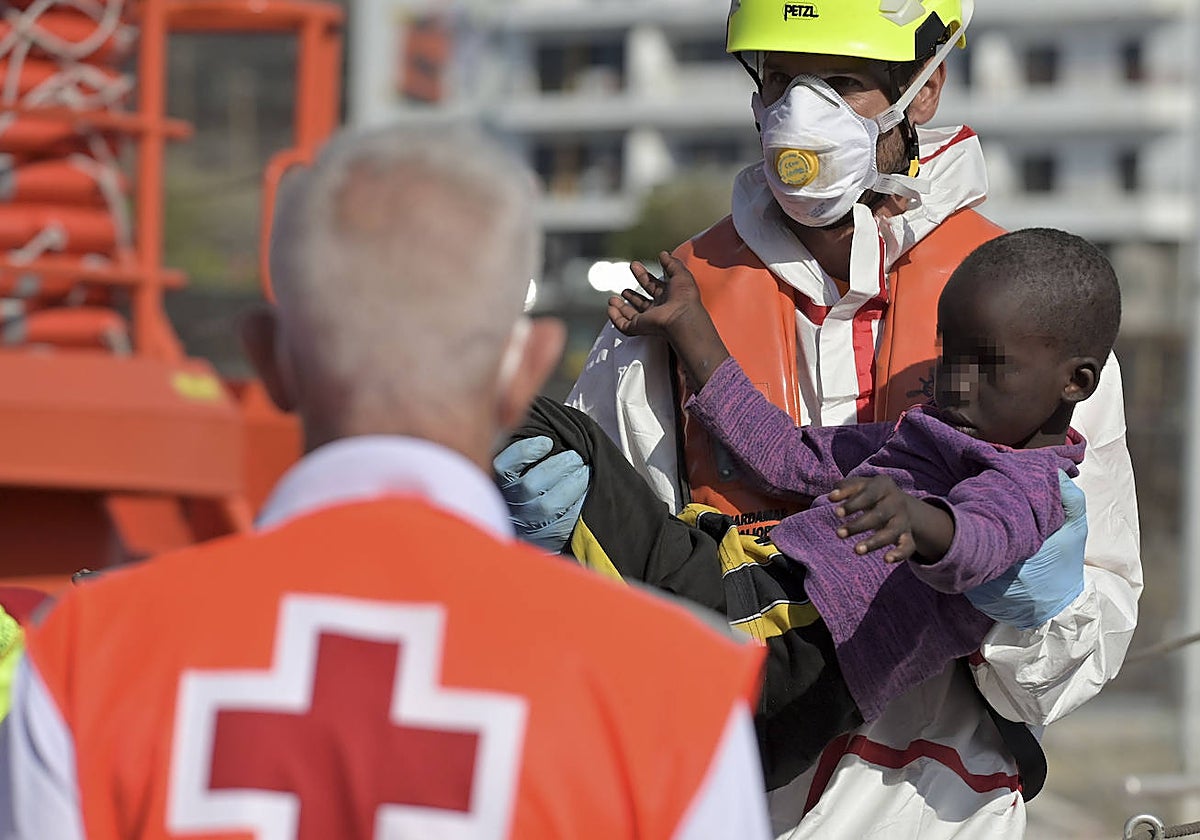 Un miembro de Salvamento Marítimo lleva en brazos un bebé tras llegar a puerto de La Restinga, El Hierro
