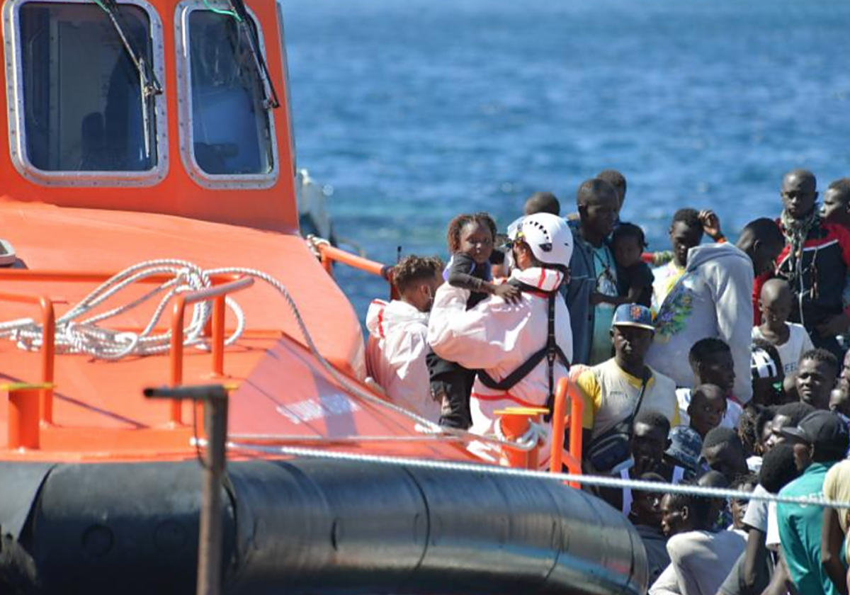 Un rescatador coge en brazos a una niña de corta edad mientras se organiza el desembarco de la Salvamar en La Restinga, El Hierro