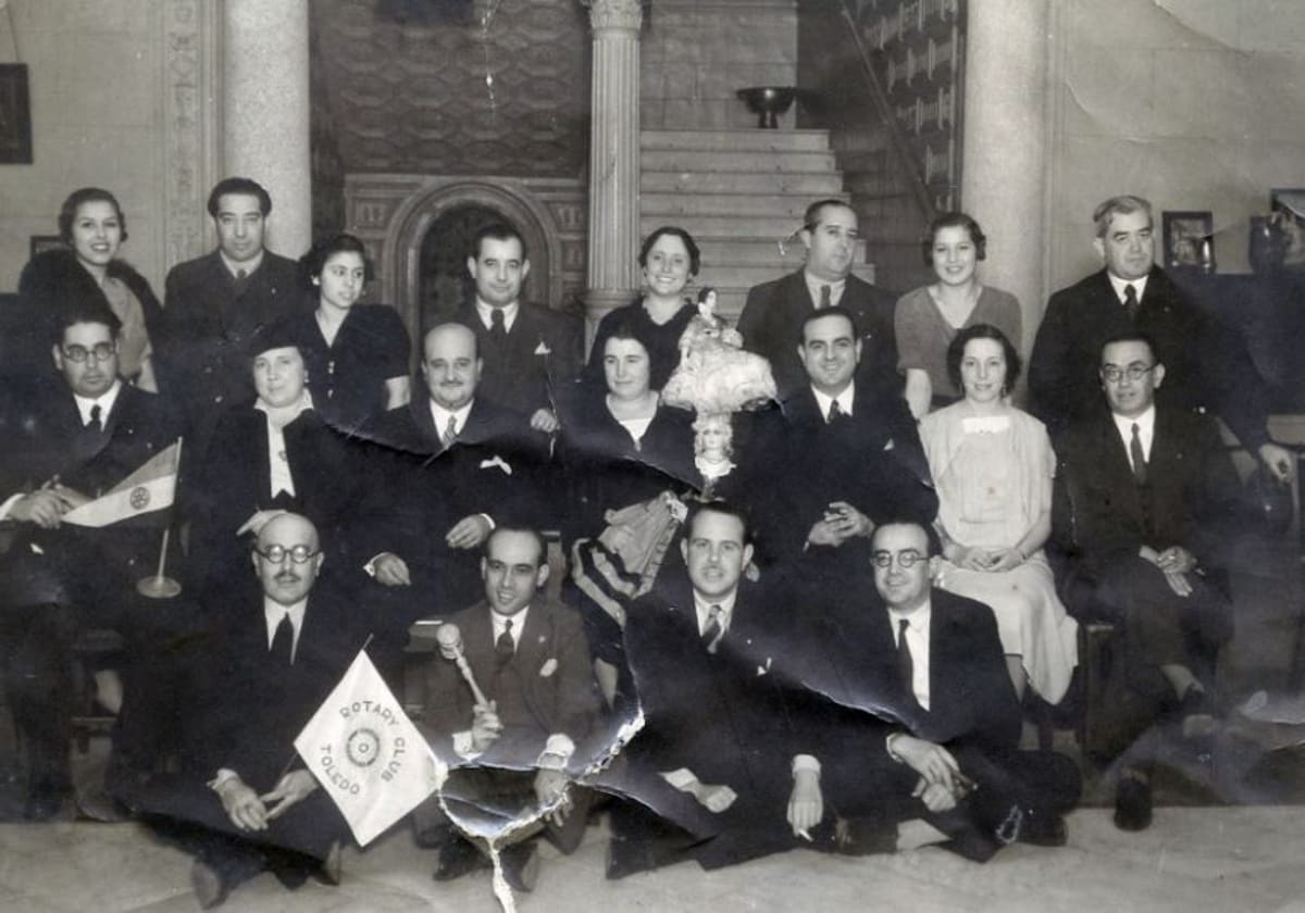 Miembros del 'Rotary Club' de Toledo posan con sus símbolos en el patio del Hotel Castilla, en 1932, para el fotógrafo Linares. Entre otras personas, Antonio Lillo, Diego Soldevilla, José Esteban Infantes, Wenceslao Manzaneque y Manuel Moro. En 1931, el Rotary Club de Alicante admitió a la primera mujer, no obstante, era habitual la participación femenina en los actos de muchos clubes. Archivo Municipal de Toledo. Colección Luis Alba