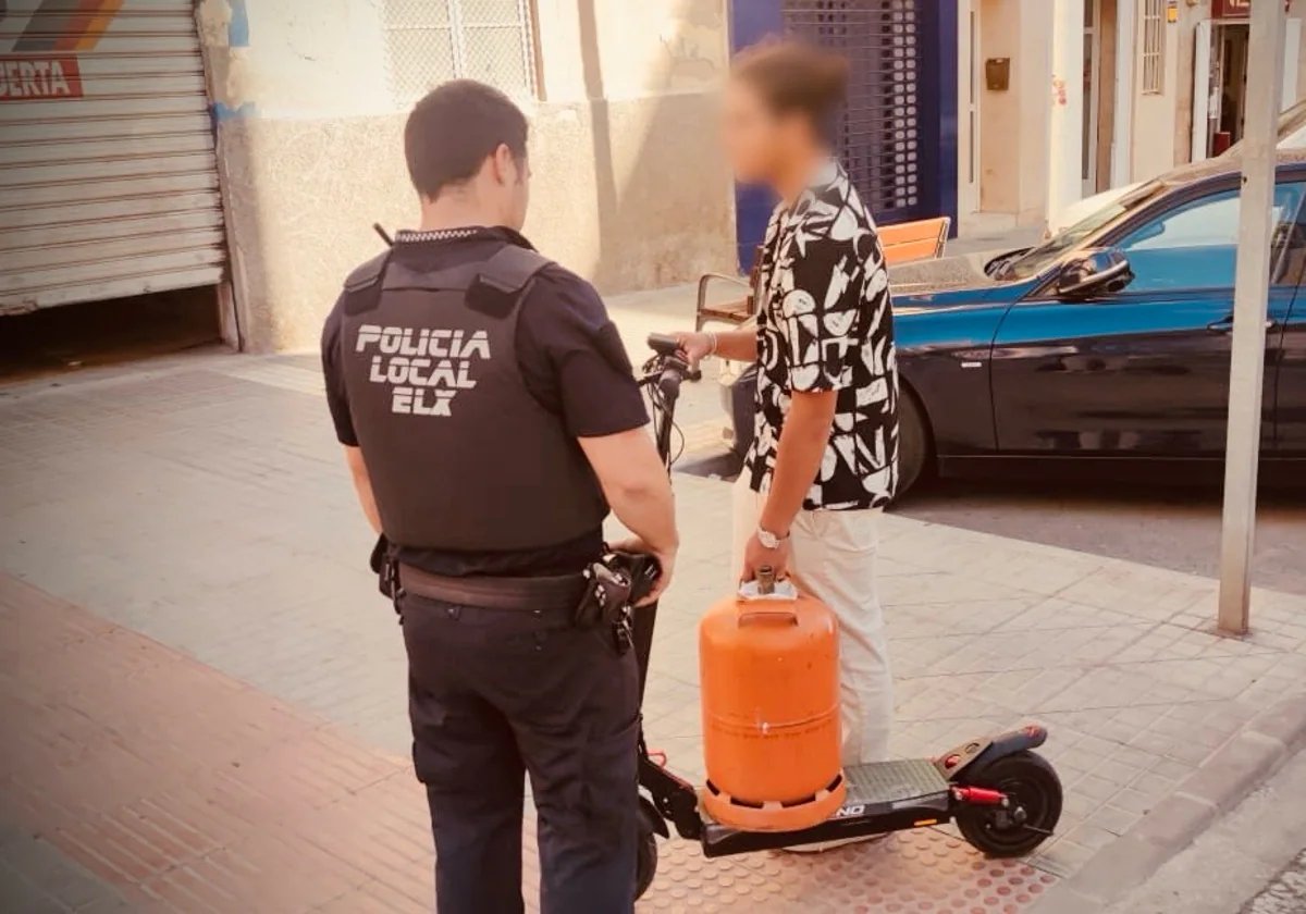 Un agente ilicitano junto al usuario de un patinete eléctrico que transportaba una bombona de butano