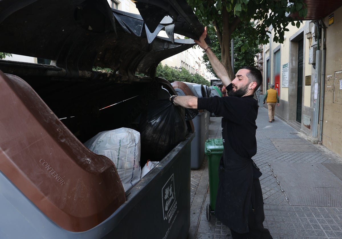 Un joven introduce una bolsa de basura en un contenedor en la calle Claudio Marcelo