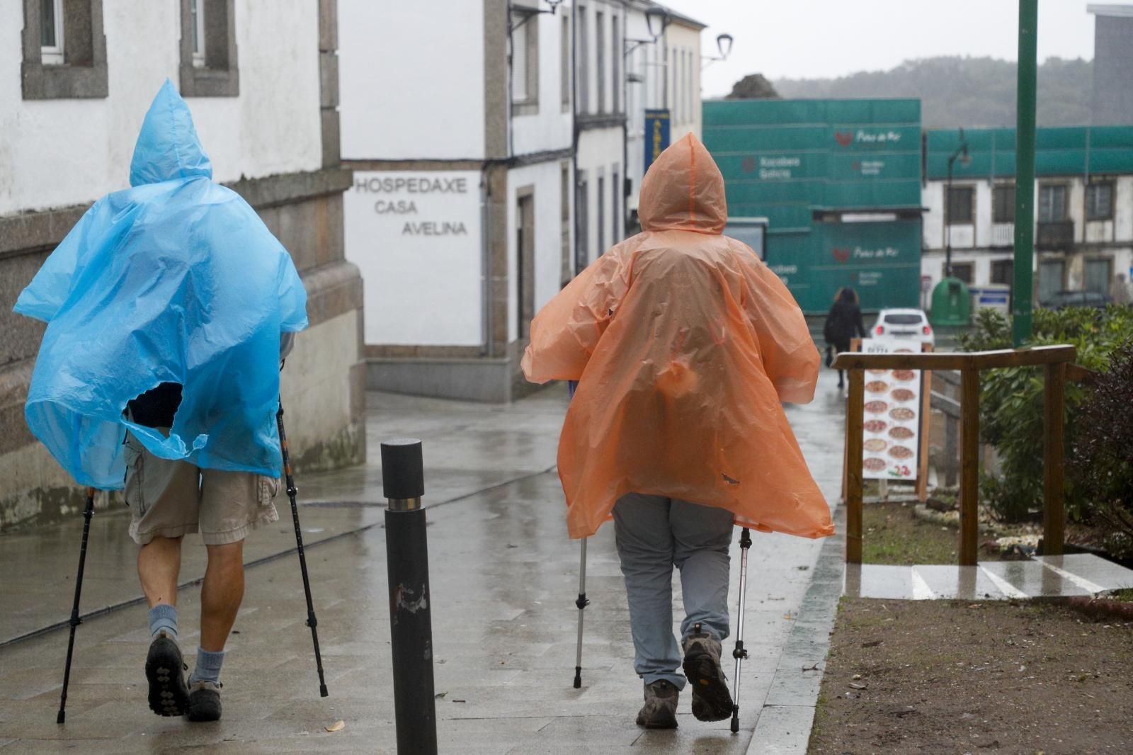 Varios peregrinos se protegen del viento y la lluvia, este miércoles en Palas de Rei