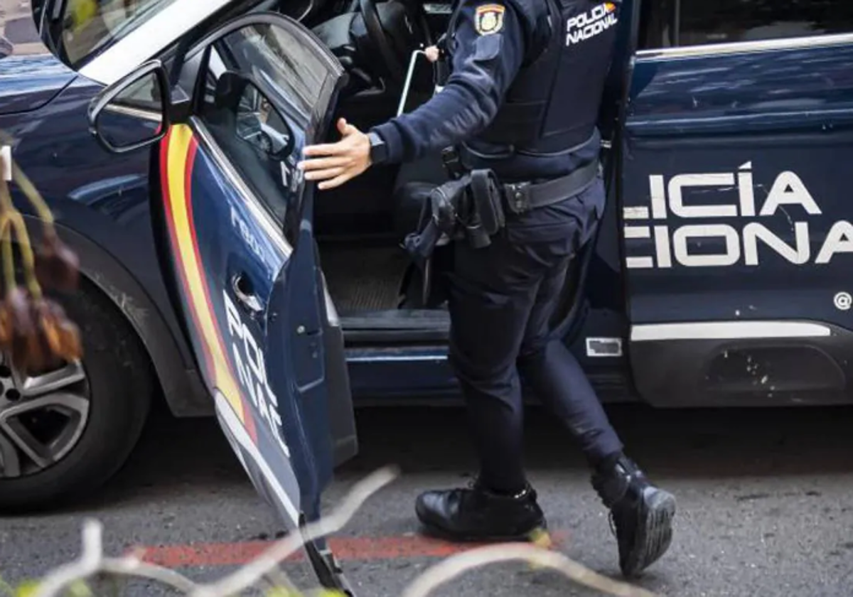 Un agente de la Policía Nacional subiéndose a un coche patrulla