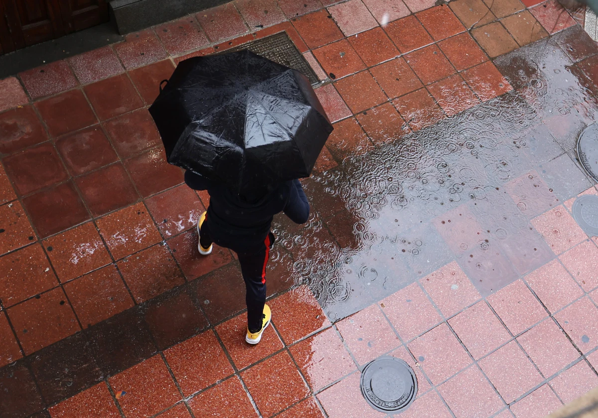 Un viandante atraviesa un charco en plena lluvia en Córdoba capital