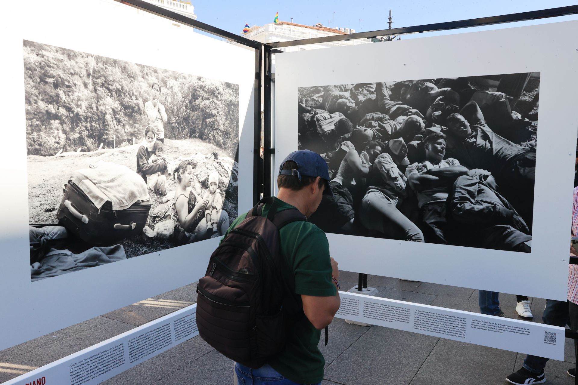 Un hombre lee el cartel explicativo de una de las imágenes de la muestra 'Bolivariano', en el que se muestran las condiciones que atraviesan quienes huyen del régimen